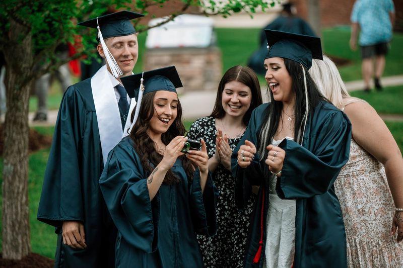 Graduates and students gather to look at camera photo